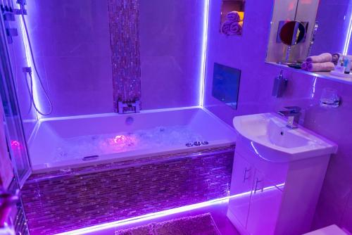 baño con bañera y lavabo con luces moradas en Meridian Serviced Apartments, en Bradford