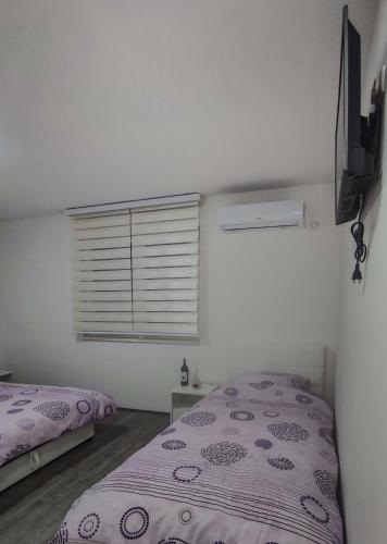 a bedroom with a bed and a window with a purple comforter at Apartmani Hani in Trebinje