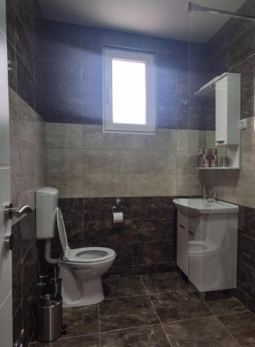 a bathroom with a toilet and a sink and a window at Apartmani Hani in Trebinje