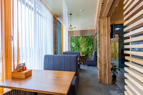 a dining room with a wooden table and blue chairs at Rich OAK - готель з відкритим панорамний басейном in Yablunytsya