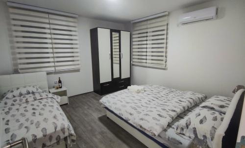a bedroom with a bed and two windows with shutters at Apartmani Hani in Trebinje