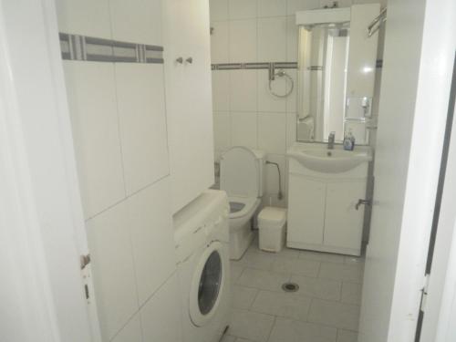 a white bathroom with a toilet and a sink at Blue and White Studios & Apartments in Lefkos Karpathou