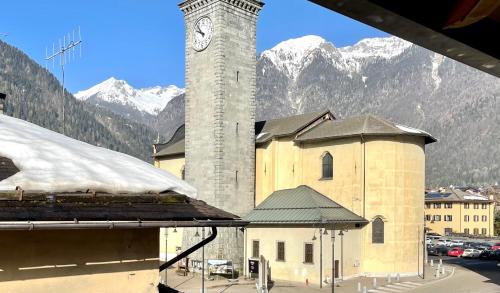 a building with a clock tower with mountains in the background at Dolomiti House in Pinzolo