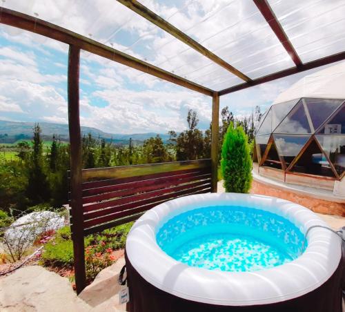 a hot tub on a patio with a pergola at Glamping NIDO VERDE in Iza