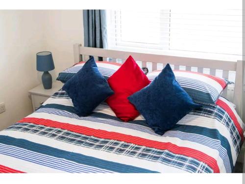 a bed with four blue and red pillows on it at The Retreat, Cromer in Cromer
