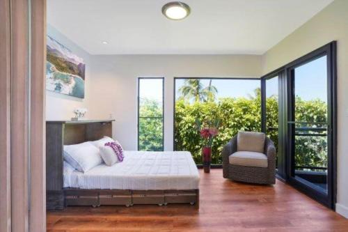 a bedroom with a bed and a chair and windows at Luxury 2-Story Oceanfront Condo w/ Views & Pool in Wailua