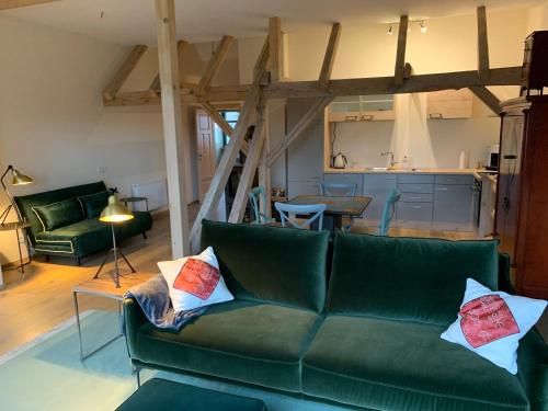 a living room with a green couch and a kitchen at Kranichhof - Studio, Loft & Atelier in Zossen