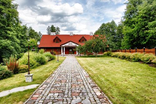 a house with a red roof and a stone path at Hotel Dworek Wapionka in Górzno