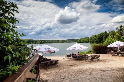 a group of people sitting on a beach with umbrellas at Hotel Dworek Wapionka in Górzno