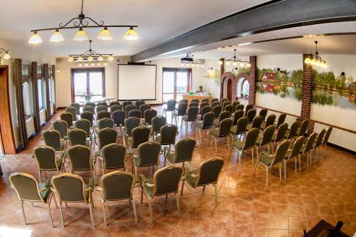 a room with rows of chairs and a projection screen at Hotel Dworek Wapionka in Górzno