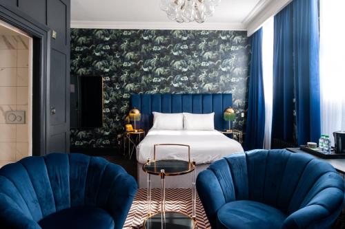 a bedroom with a bed and two blue chairs at Lock and Key Boutique Hotel - Duke Street in Liverpool