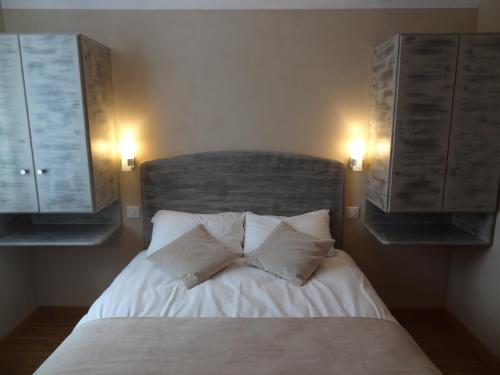 a bedroom with a bed with two pillows and two cabinets at Merveilles88 in Rupt-sur-Moselle