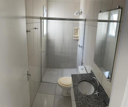 a white bathroom with a toilet and a shower at Residencial Costa Maré in Torres