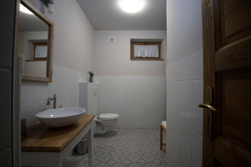 ein weißes Bad mit einem Waschbecken und einem WC in der Unterkunft Egyszervolt Házikó in Tiszafüred