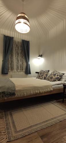 a bedroom with a large bed with a chandelier at Egyszervolt Házikó in Tiszafüred