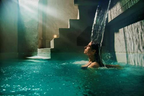 un uomo in una piscina sotto una cascata di A.P. Acropolis View Apartments ad Atene