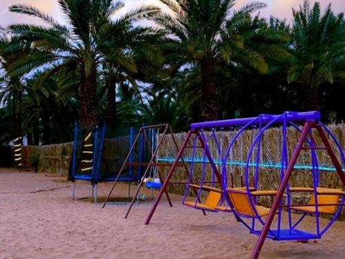 um parque infantil numa praia com palmeiras ao fundo em أستراحة مون لايت الريفي em Al-ʿUla