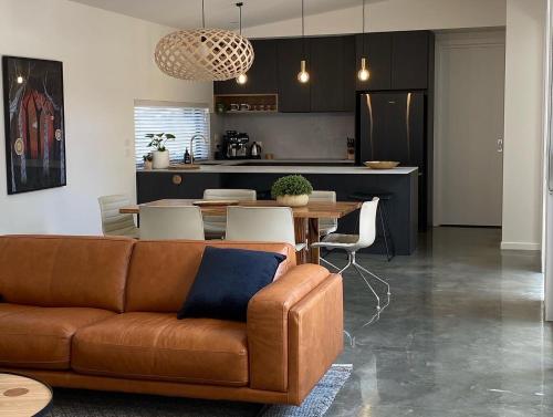 a living room with a couch and a table and a kitchen at The Little House in Inverloch