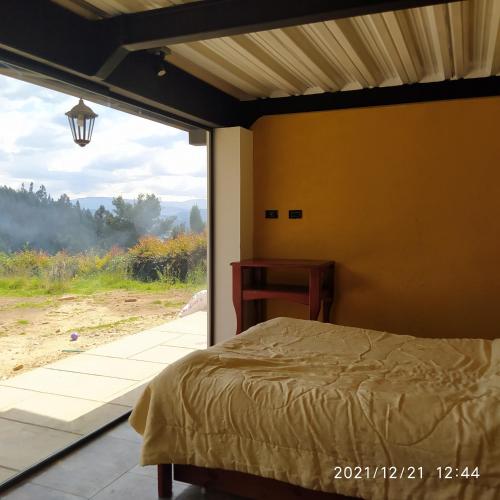 a bedroom with a bed and a large window at Refugio MALUAN.. Cabaña Villa Nepo in Paipa