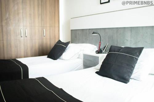 a bedroom with two beds with white sheets and black pillows at Brand New - Prime Location For All Budgets - Executive & Luxury in Barranquilla