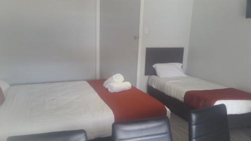 a hotel room with two beds and a chair at Wauchope Motel in Wauchope