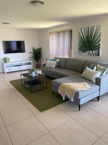 a living room with a couch and a tv at Mudgee House in Mudgee