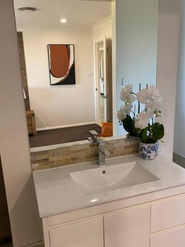 a bathroom with a sink and a vase of flowers at Mudgee House in Mudgee