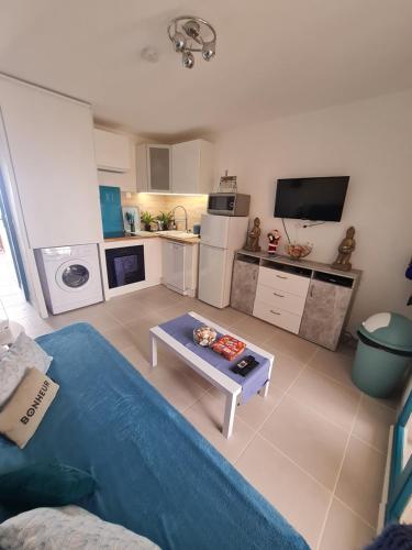 sala de estar con sofá azul y mesa en appartement vue mer pour 4 personnes accès direct plage wifi haut débit gratuit en Le Barcarès