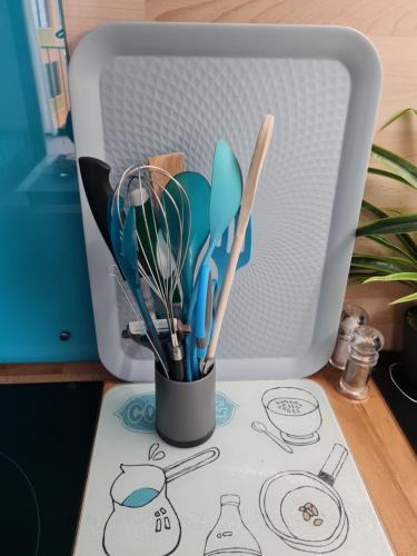 a cup with utensils on a table next to a microwave at appartement vue mer,accès direct plage,fibre,clim,parking public gratuit in Le Barcarès