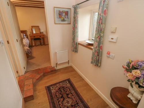 a hallway with a stairway with a vase of flowers at Old Tether Barn in Whitechurch