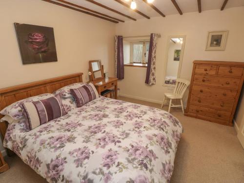 a bedroom with a bed and a dresser at Old Tether Barn in Whitechurch