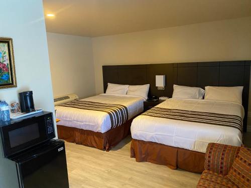 a hotel room with two beds and a television at Silver Maple Motel in Haliburton