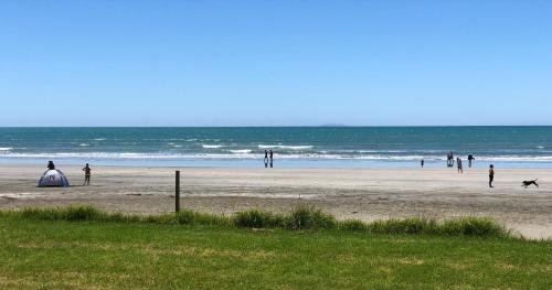 a group of people standing on a beach at Beachpoint Apartments in Ohope Beach