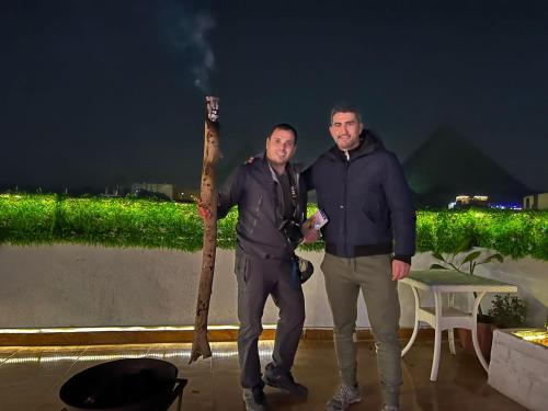 two men are standing next to a tree branch at Pyramids Top Inn in Cairo
