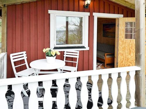 a porch of a red house with a table and chairs at 7 person holiday home in ALLINGSÅS, SVERIGE in Hjälmared