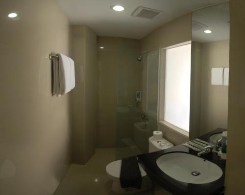 a bathroom with a sink and a toilet and a mirror at Vio Cihampelas in Bandung