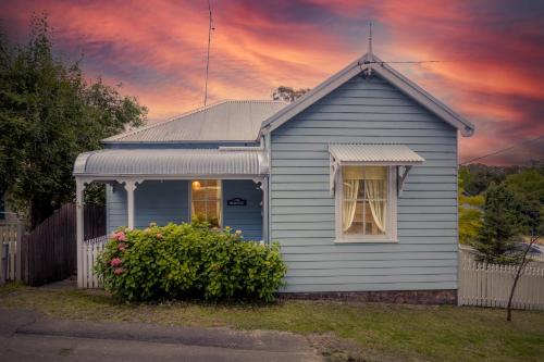 a blue house with a window and a bush at Pet-Friendly Blue Mountains Cottage with Indoor Fireplace in Mount Victoria
