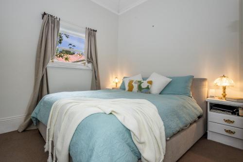 una camera da letto con un letto blu con una finestra di Pet-Friendly Blue Mountains Cottage with Indoor Fireplace a Mount Victoria