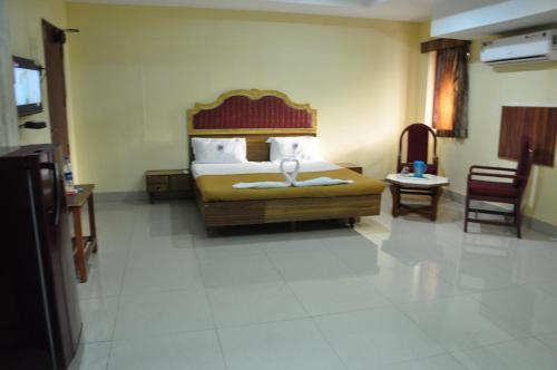 a bedroom with a bed and a chair in it at Hotel Chanma International in Coimbatore