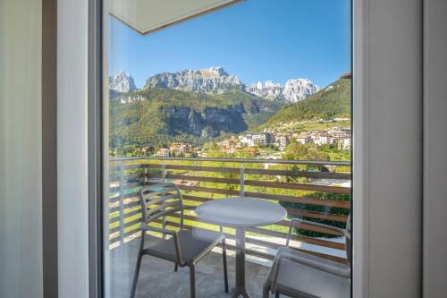 a balcony with a table and chairs and mountains at Hotel Fontanella in Molveno