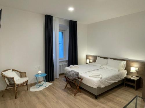 een slaapkamer met een bed, een stoel en een raam bij Al Palazzo in Cles