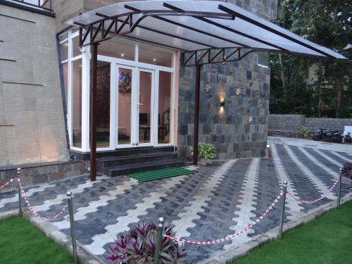 a patio with an umbrella on a house at Laughing Waters Fine Stay in Kuttālam