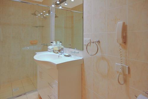a bathroom with a sink and a shower with a phone at Oasis Inn Ulladulla - Welcoming Guests 18 Years and Older in Ulladulla
