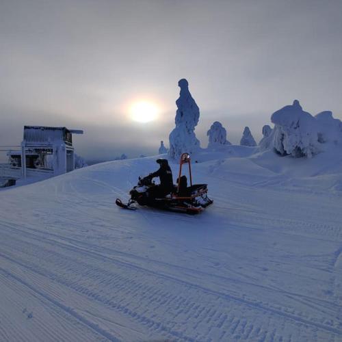 a person riding a snowmobile down a snow covered slope at Nilsiä city, Tahko, 80 m2, Incude x2 Ski Pass in Tahkovuori