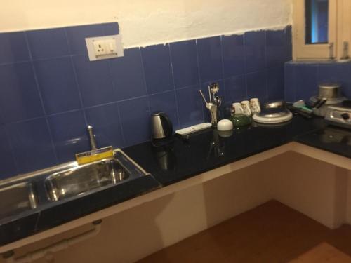 a kitchen counter with a sink and blue tiles at Stupa Guest House in Bīr