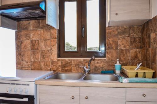 a kitchen with a sink and two windows at Villa Irena panoramic sea view in Agalianós
