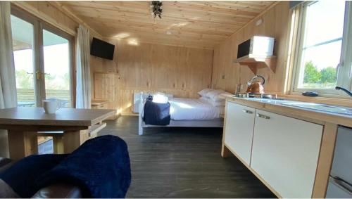a bedroom with a bed and a kitchen with a sink at Beautiful Wooden tiny house, Glamping cabin with hot tub 3 in Tuxford