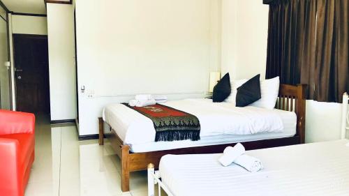 a hotel room with two beds and a red chair at EZ House in Sukhothai