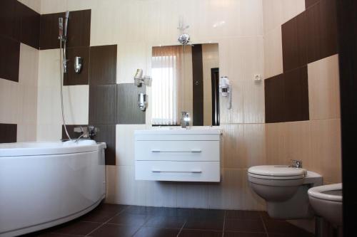 a bathroom with a toilet and a tub and a sink at Hotel Ukraina in Voronezh