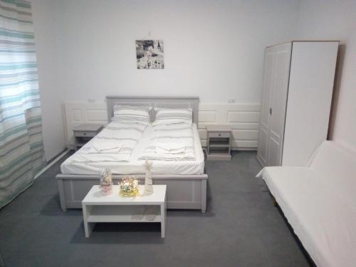 a white bedroom with a bed and a table at Cazare SPORT CONFORT in Hunedoara